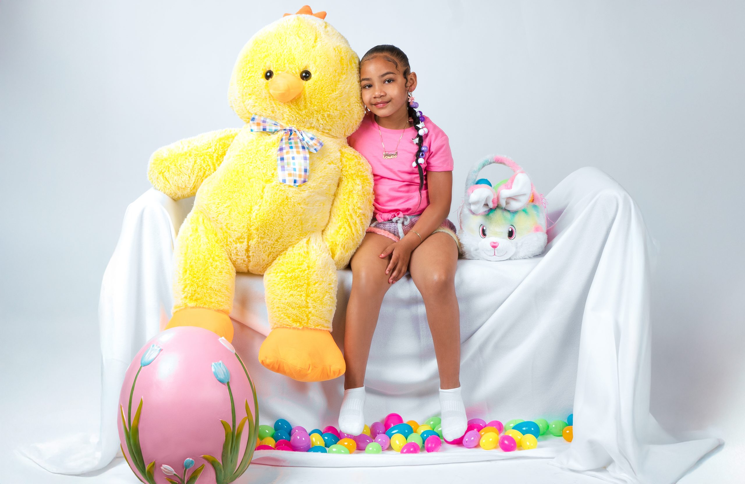 Girl seated beside a large stuffed chick with Easter decorations