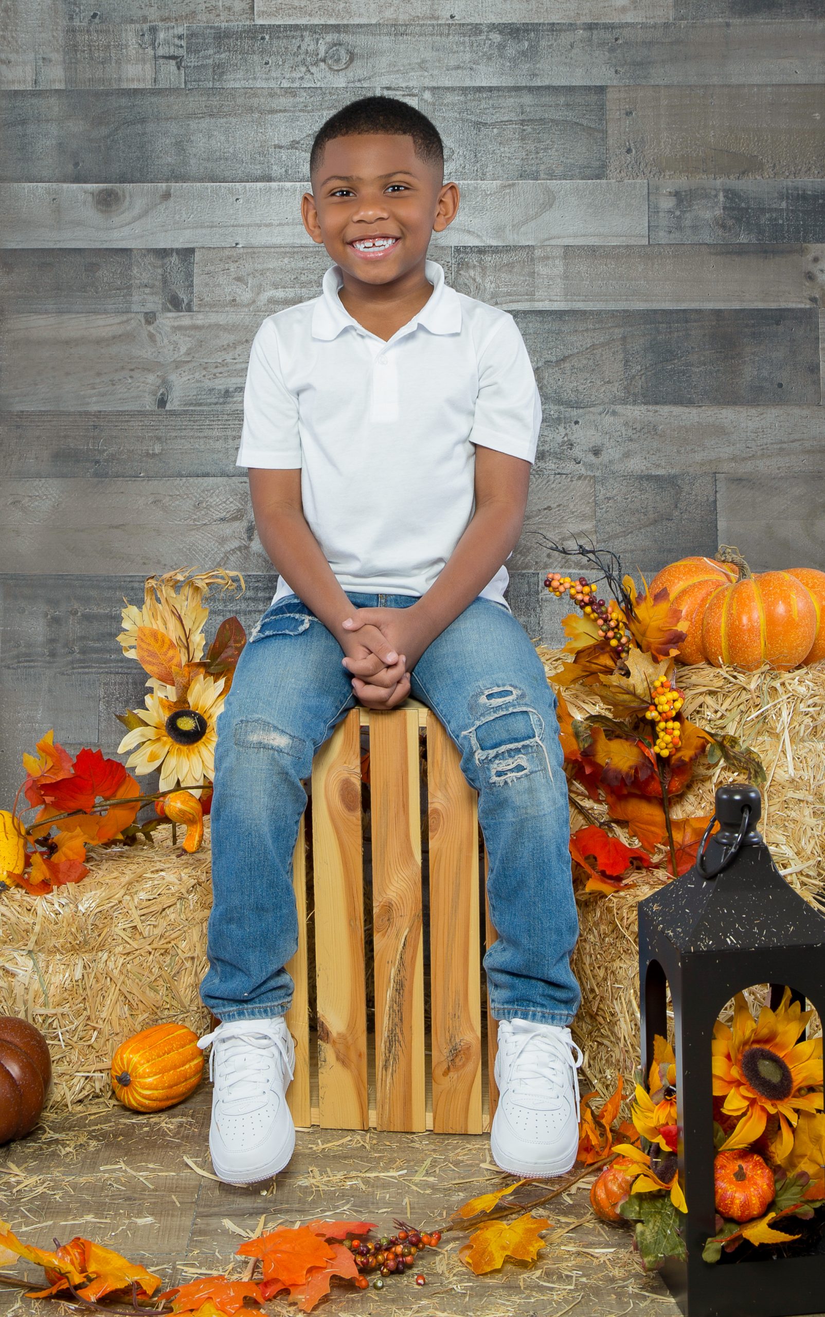 Smiling boy seated on a crate with a Thanksgiving themed set