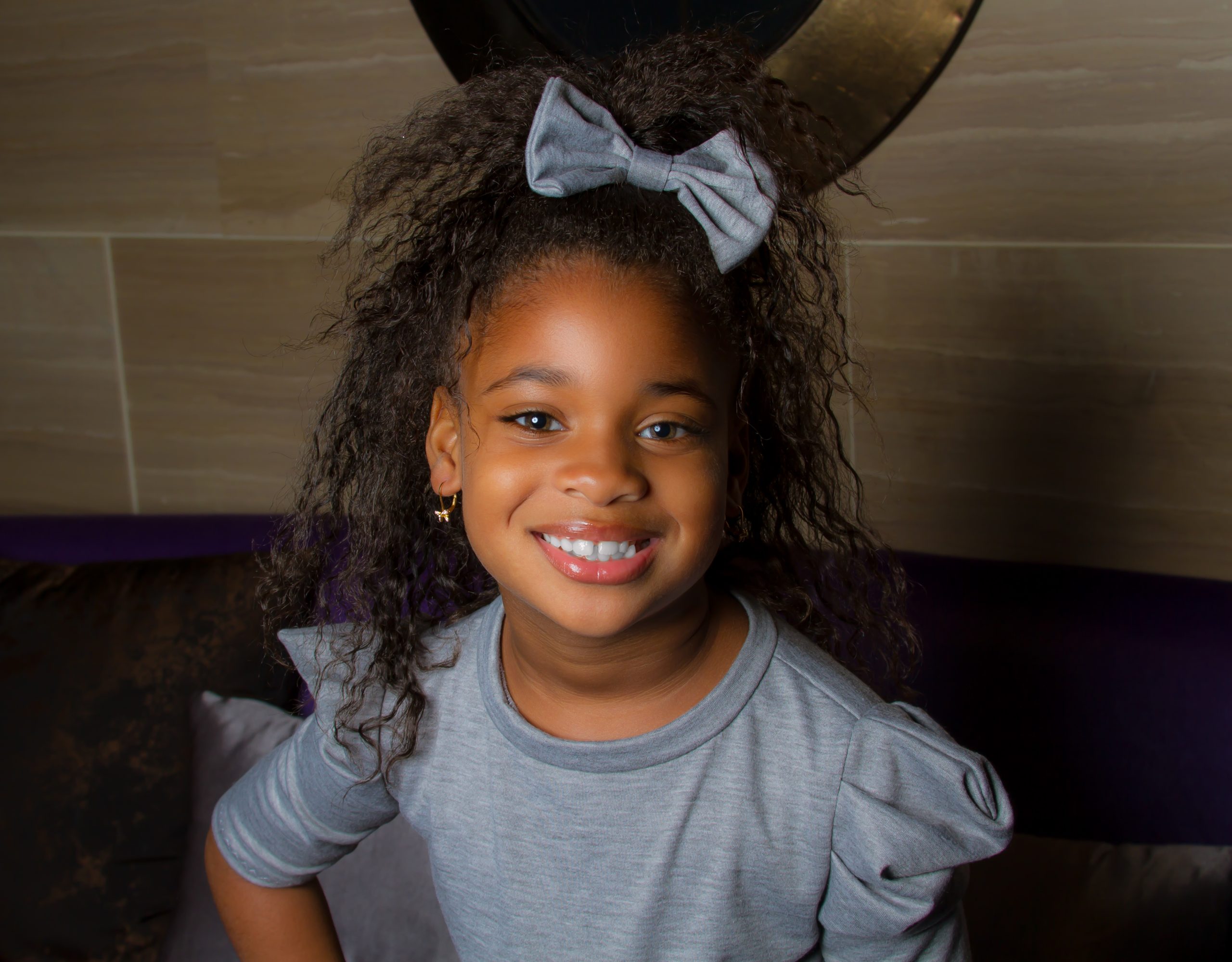 Smiling girl with a gray bow and gray top