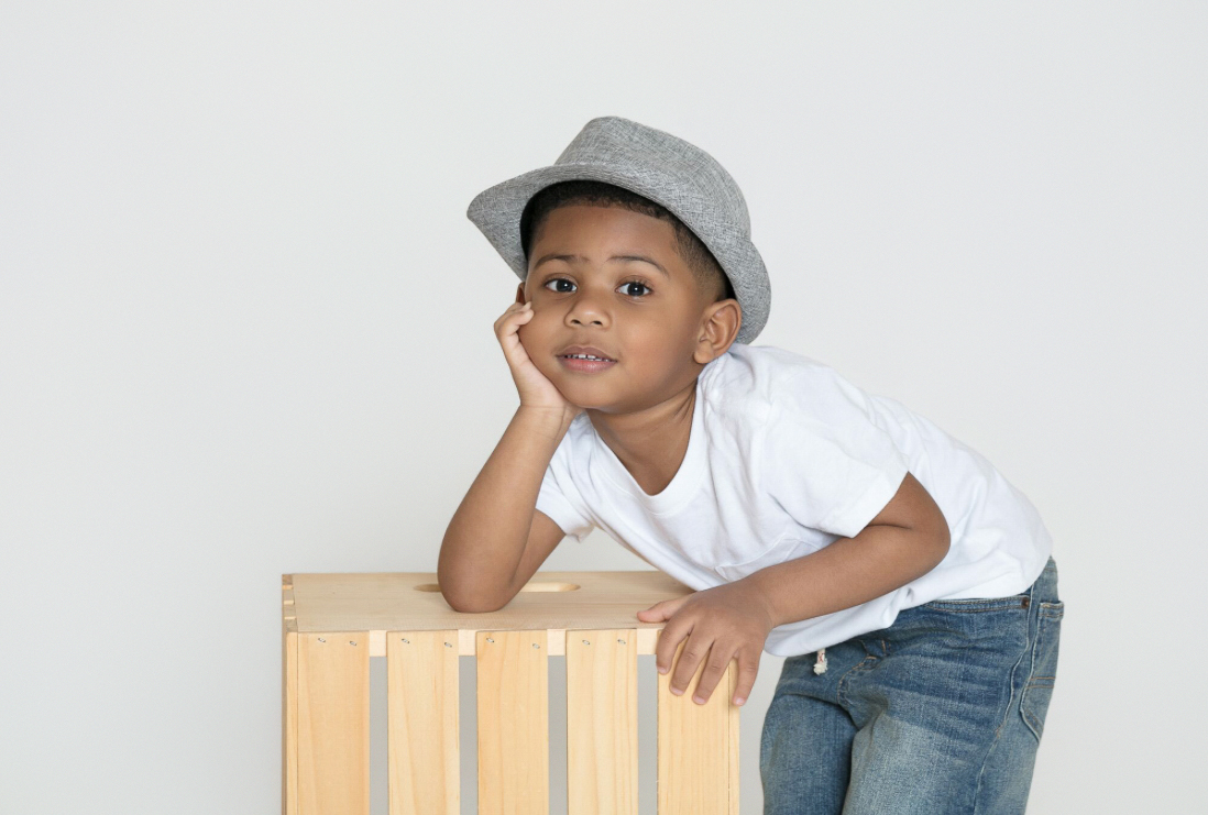 Boy in a gray hat leaning on a wooden crate