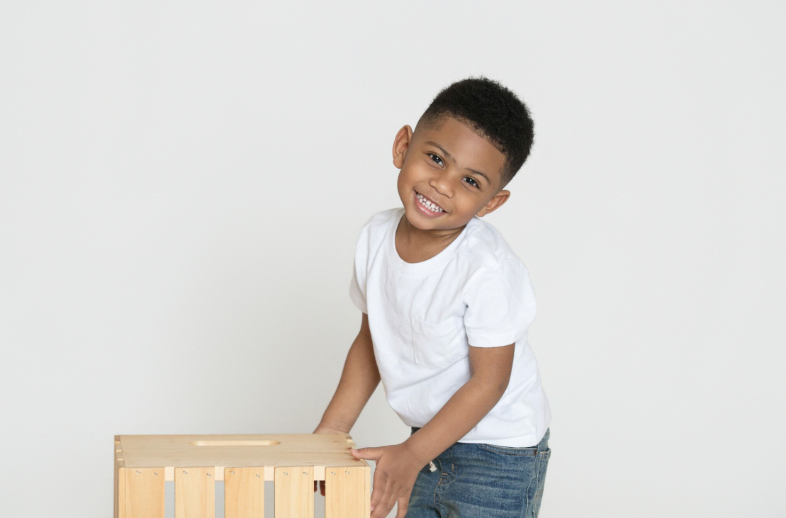 Smiling boy leaning on a wooden crate
